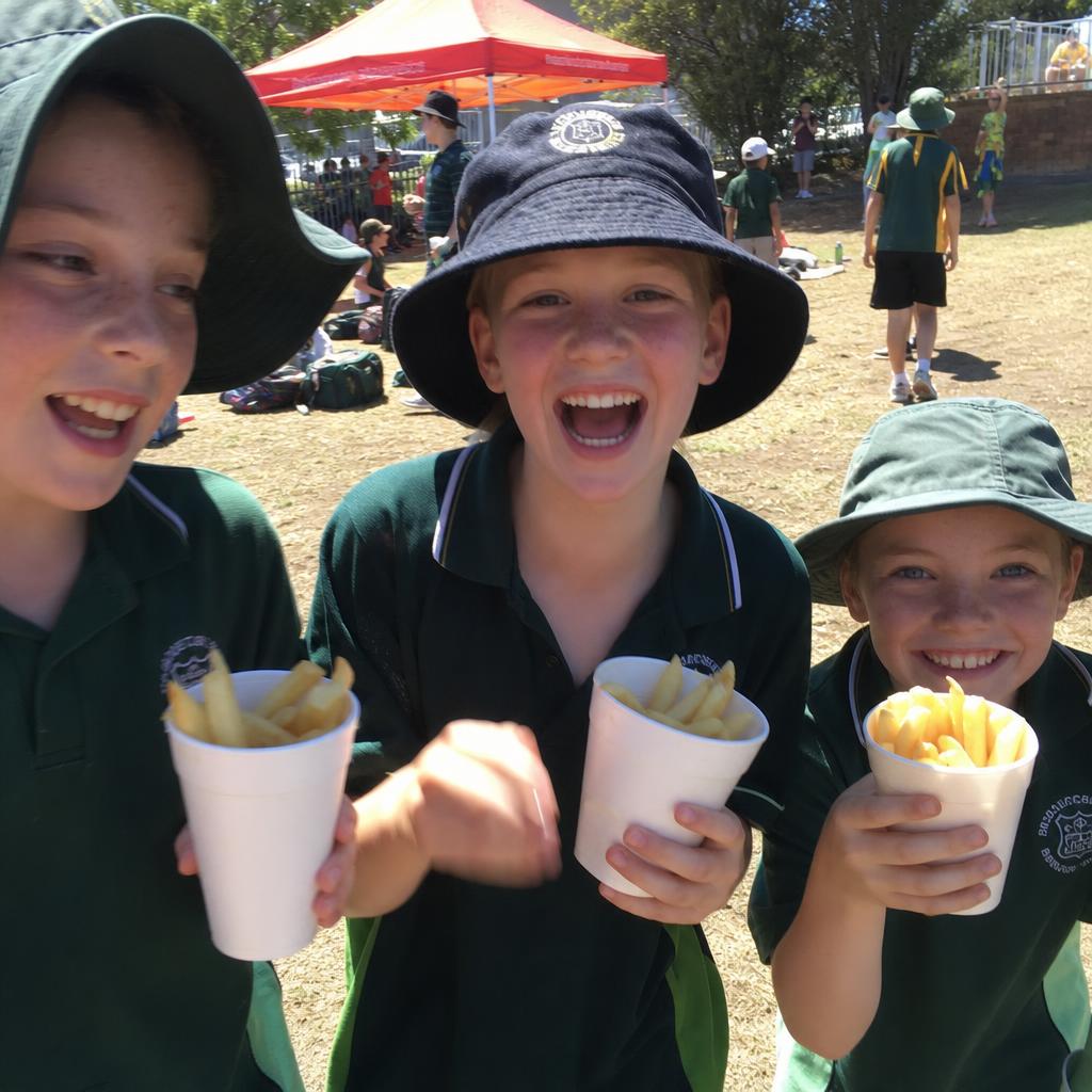 Kids at a school carnival eating fresh hot chips